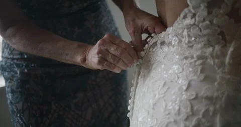 Mother buttoning lacy expensive wedding dress of her daughter, back closeup Video stock 172609998