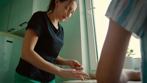 Mother carefully folding dough while preparing dumplings near kitchen window Stock Footage 303282043