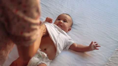 Mother changes clothes of the baby lying on the bed Stock Footage 201113933