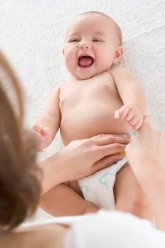 Mother changing baby's diaper indoors Stock Photos