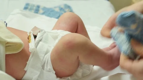 Mother changing wool socks of newborn baby laying on table Stock Footage 71591949
