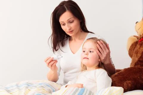 Mother Checking Her Daughter's Temperature Stock Photos