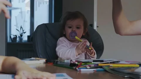 Mother checking lessons at the son, baby girl sittingin high chair playing with Stock Footage 172227345