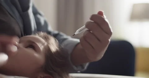 Mother checking temperature of child on sofa Stock Footage 200931547