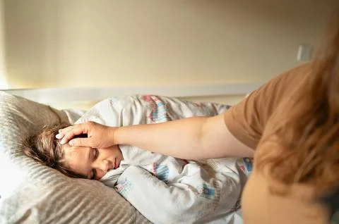 Mother checking temperature with hand of ill daughter. Sick child lying on bed Stock Photos