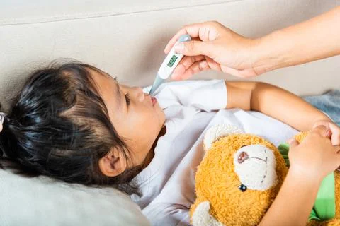Mother checking temperature of her sick daughter with thermometer in mouth Stock Photos