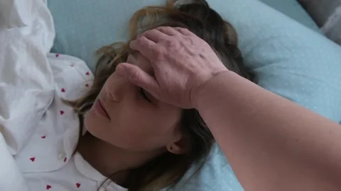 Mother checks child’s temperature by touching forehead while girl Stock Footage 331597262