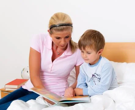 Mother with child in bed to read the stories. Stock Photos
