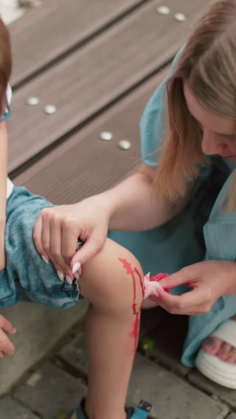 Mother Cleans Her Son s Injured Leg as He Sits Uncomfortably Stock Footage 316970880