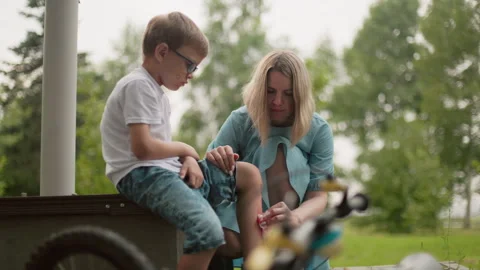 Mother Cleans Son's Bleeding Leg After Bicycle Accident Stock Footage 287380108
