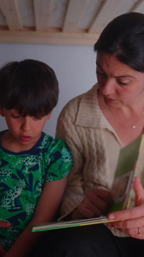 Mother coaching child through reading practice during evening routine, high.. Stock Footage 337410974