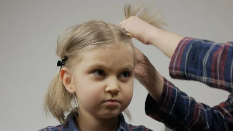 A mother combs her four-year-old daughter's hair on a blonde head. Stock Footage 147288473