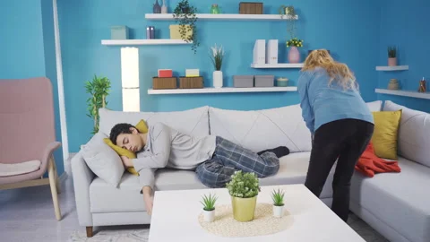 Mother covering blanket over her son who fell asleep on the sofa. Stock Footage 233072853