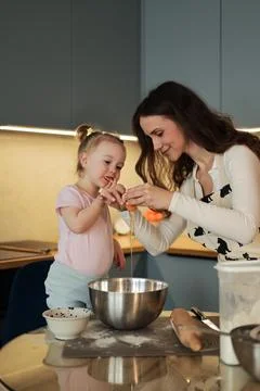 Mother Cracking Egg into Bowl While Toddler Watches Foto stock