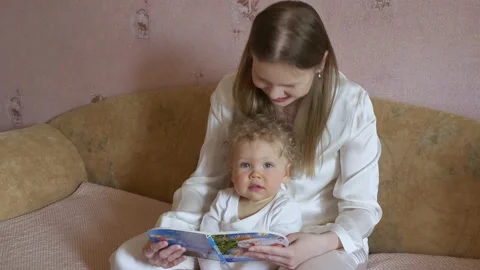 Mother with a cute baby have fun looking at the picture book. Video stock 130809341