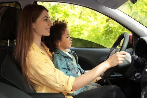 Mother with cute little daughter driving car together. Child in danger Stock Photos