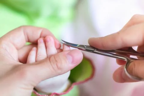 Mother is cutting tiny nails neatly and gently on the hand of newborn using nail Stock Photos