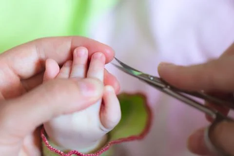 Mother is cutting tiny nails neatly and gently on the hand of newborn using nail Stock Photos