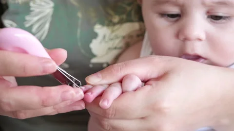 Mother cutting upset baby son nails Stock Footage