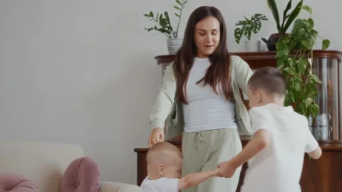Mother dancing in circle with two young sons holding hands at home Stock Footage 315749120