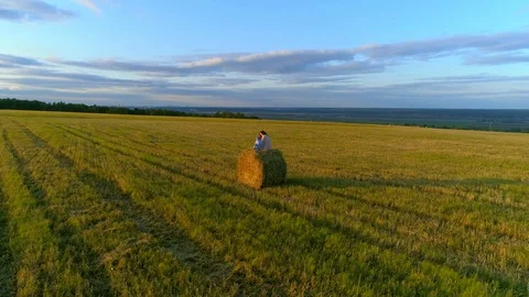 Mother with daughter sit on the straw stack on the rustic field in the sunset. Stock Footage 85667782