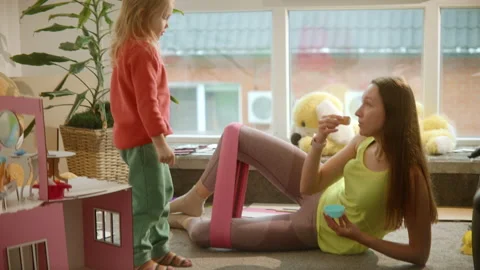 Mother does sport exercises while playing with daughter at nursury room, workout Stock Footage 234054128