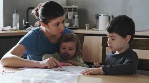 Mother doing homework with her son pointing to something written in his notebook Stock Footage 172506487