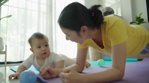 Mother doing plank exercise with her baby boy at home. Stock Footage 168348422