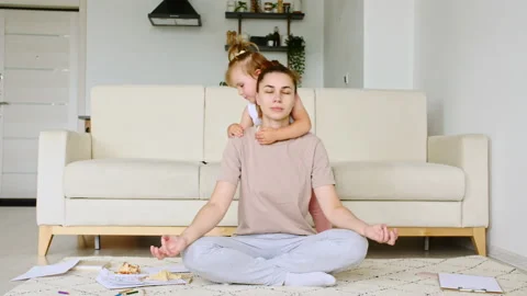 Mother doing yoga exercise at home for stress relief relaxing, while her child Stock Footage 162948801