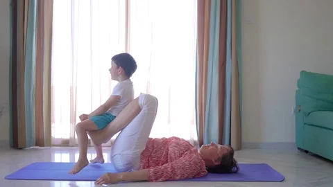 Mother doing yoga workout at home with cute young son Stock Footage 76908983