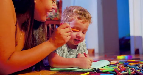 A mother is drawing with crayons in a notebook together with her son Видео 170730193