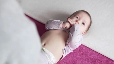 Mother dressing her six month baby daughter in bed lying on her bed Stock Footage 273743232