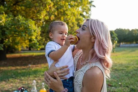 Mother eats an apple given by her son during a picnic, healthy eating concept Stock Photos