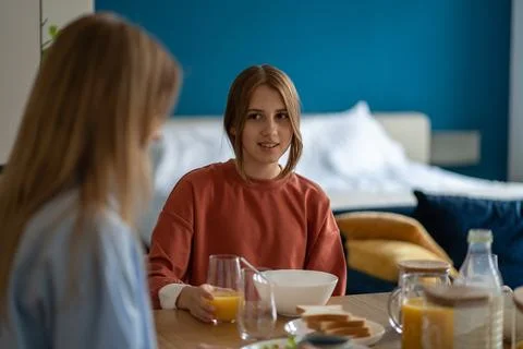 Mother eats breakfast and talks daughter about school, share secrets. Family Stock Photos
