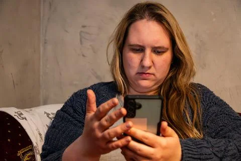 Mother engaged with smartphone while seated comfortably at home in cozy sur.. Stock Photos