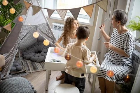 Mother explaining children early development sensory sandbox tasks preschool Stock Photos