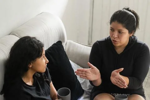 Mother explaining something with hand gestures while her daughter listens a.. Stock Photos