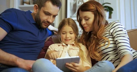 Mother, father and daughter using tablet, playing games and having fun. Family Stock Footage 74284409