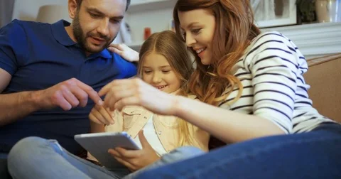 Mother, father and daughter using tablet, playing games and having fun. Family Stock Footage 74284552