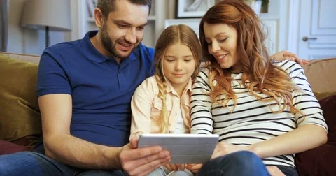 Mother, father and daughter using tablet, playing games, watching videos and Stock Footage 74286583