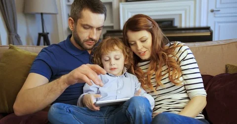Mother, father and son using tablet, playing games, watching videos and having Stock Footage 74286705