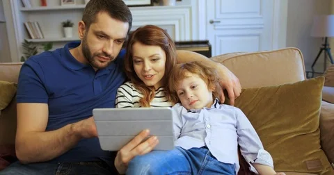 Mother, father and son using tablet, watching movie. Tapping and scrolling touch Stock Footage 74286779