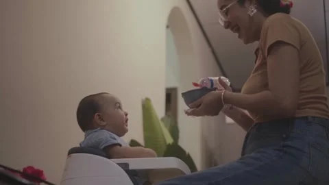 Mother feeding her infant son at home Stock Footage 341892433