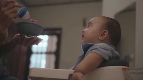 Mother feeding her smiling son with a spoon 스톡 동영상 341892175