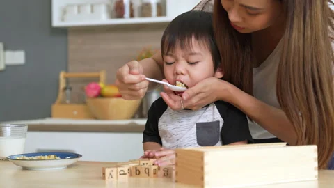 Mother feeding her son while the little boy was playing with toys. Stock Footage 205123837
