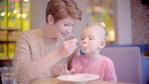 Mother feeds her son with a spoon Stock Footage 72491960