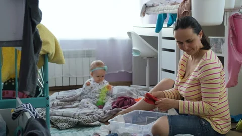 Mother folding clothes while her baby playing Vídeo Stock 243929796