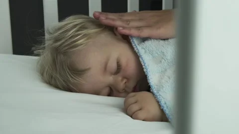 Mother gently stroked the sleeping baby's head and hair in a child's cot crib Stock Footage 149237223