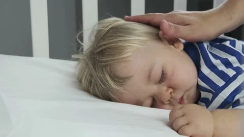 Mother gently stroked the sleeping baby's head and hair in a child's cot crib Stock Footage 149237227