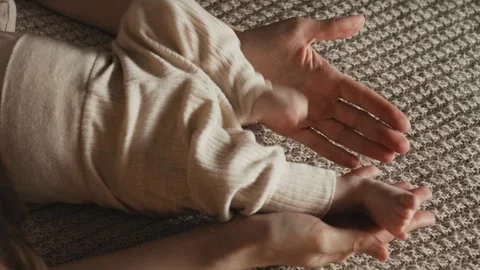 Mother gently touching moving legs of baby lying on blanket Video stock 335839792